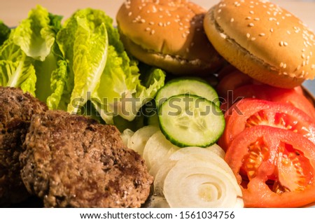 Burger ingredients with patties salad tomatoes onions and buns