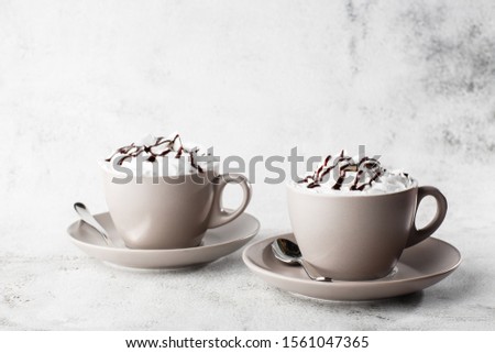 Two cups of coffee with whipped cream and chocolate topping. Iced coffee in white cup isolated on bright marble background. Overhead view, copy space. Advertising for cafe menu. Coffee shop menu