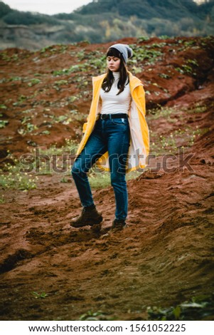 Young beautiful girl with yellow jacket posing at clay quarry.