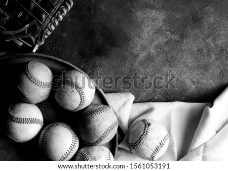 Texture of old baseballs with glove, copy space on black and white grunge background.