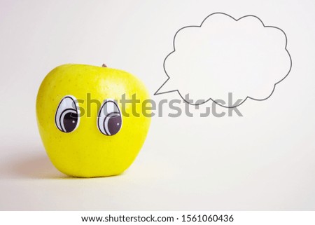 Green apple with eyes looking to the side. Funny cute picture of fruits. Light background, place for text.