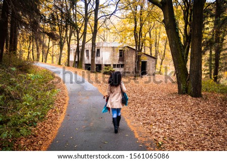 Woman walking in the rain on asphalt forest road at autumn. Road next to the Tresnja lake in Serbia.