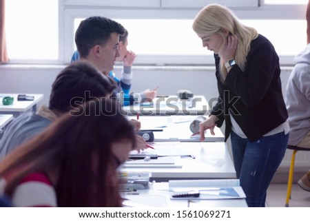 Beautiful young female teacher helping a student during class. Female Professor Holding Lecture to Multi Ethnic Group of Students. Smart Young People Studying at the University.