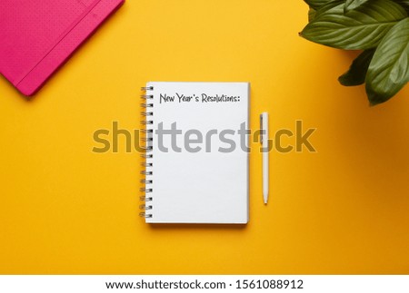 Stock photo of new year notebook with list of resolutions and objects on yellow background