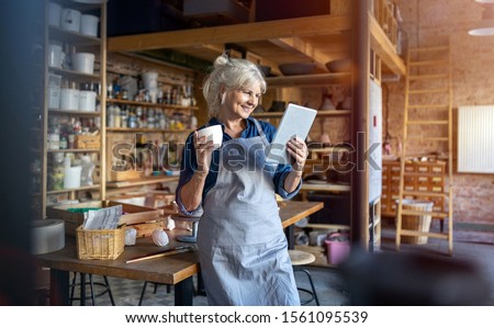 Senior craftswoman with tablet computer in art studio 
