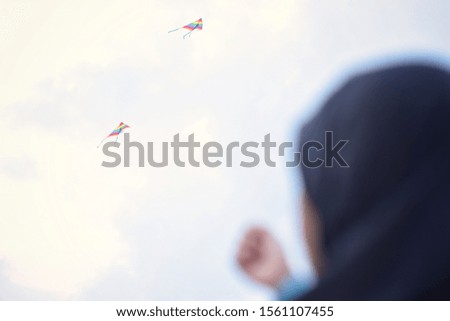 kids wear hijab with blured image playing a kite.