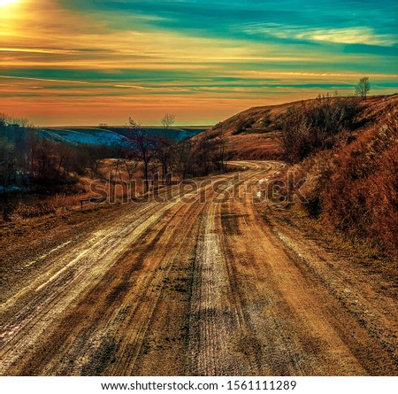 A curvy dirt road in North Dakota at sunset with interesting and alien color editing.