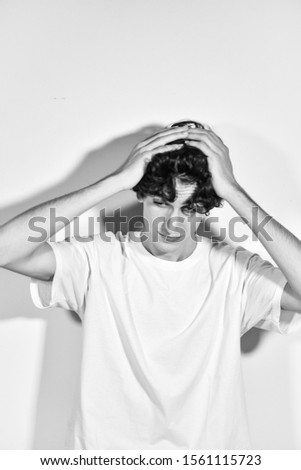 black and white photography. portrait of handsome young Italian model boy with dark curly hair posing for a fashion shooting on white background