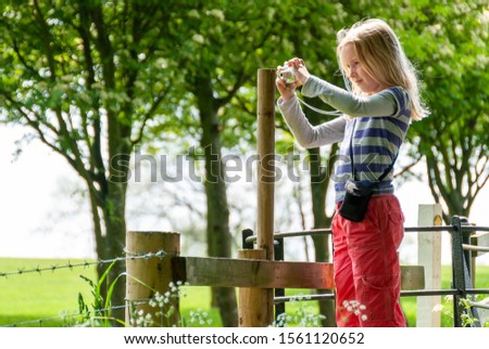 Young girl taking a photo with a point and shoot camera in a rural setting