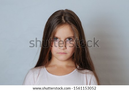 Little pretty girl with long hair, age 6-7 years old, expresses aggressive evil emotions Royalty-Free Stock Photo #1561153052