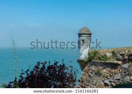 Guardhouse with litle windows in the corner of stone wall in a fortress on background of sea and blue sky. Cabin security was used by soldiers to guard the coast of invading boats.