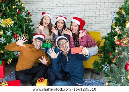 Group of asian friends taking selfie with friend together by smartphone at home during chrismas eve party or New year celebrate party. Happy winter Xmas and Happy new year party concept