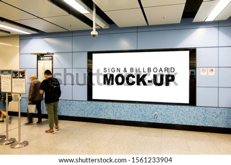 Mock up large blank horizontal billboard with clipping path placed near entrance and walkway in metro station, blurred people walking, empty space for advertising or information, advertising concept