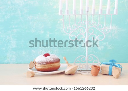 religion image of jewish holiday Hanukkah with menorah (traditional candelabra), spinning top and doughnut over pastel blue background