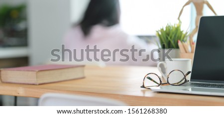 Close-up view of comfortable workplace with open blank screen laptop computer and office supplies with blurred office background
