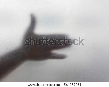 The hand that made the image of the dog's head open its mouth under the blurry glass surface.