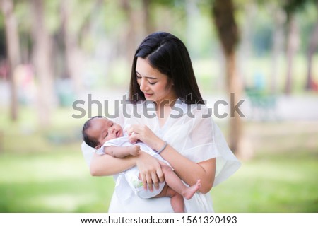 ็Healthy Asian woman mother, raising a baby in a green garden atmosphere, having a good environment, giving love and warmth.