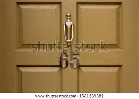 Golden door number 65 with door knocker