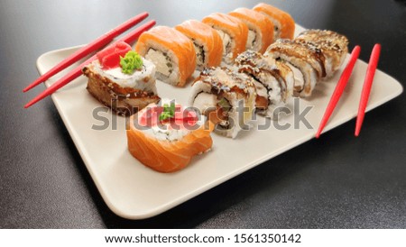 Beautiful of sushi rolls with red chopsticks on a plate.