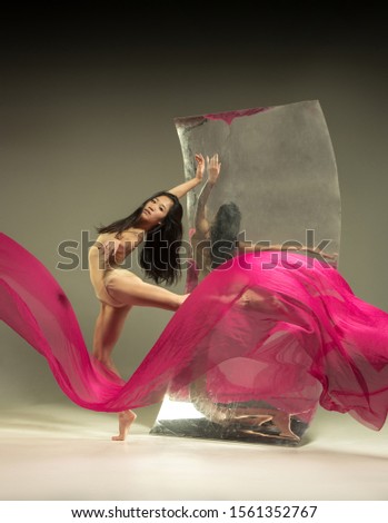 Full of feelings. Modern ballet dancer on brown background with mirror. Illusion reflections on surface. Magic of flexibility, motion with fabric. Concept of creative art dancing, action, inspiring.