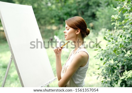 young woman paints a picture on canvas
