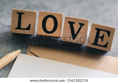 Sharp pencil, card and evelope with LOVE cube word . Concept for love story or letteror message, togetherness of friendship or family or couple or lover, wedding inviation. Be my Valentine.
