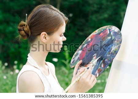 beautiful woman in nature draws on canvas