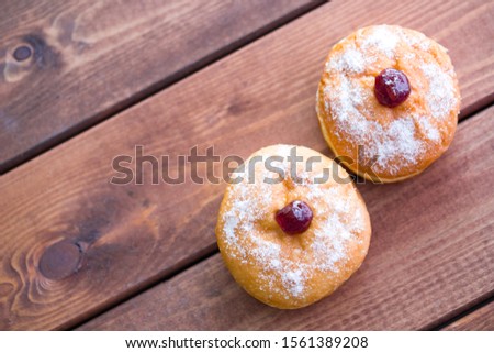 Two doughnuts with strawberry jam on wooden background.