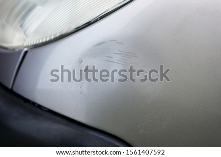 Macro of fender bender on silver gray car with scratches. Car with damage from crash accident, parking lot or traffic. Royalty-Free Stock Photo #1561407592
