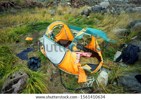 torn by a frantic hurricane wind, a cheap inexpensive tent suggests that it is important to buy high-quality branded equipment outdor in the mountains and travel

