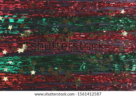 red and green stripes of tinsel on a black background. decor of gold stars. new year concept. top view, flat lay