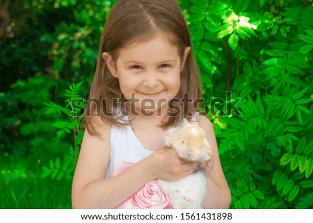 Portrait of a girl with a hare in their hands. The face of the child close up. Man and rabbit.