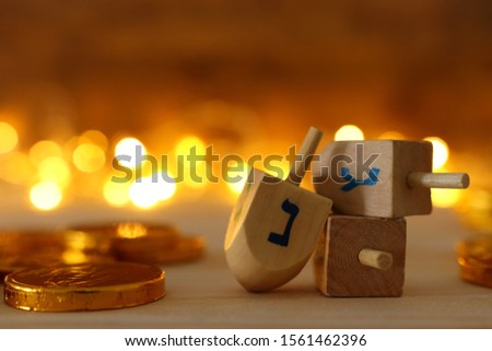 religion concept of of jewish holiday Hanukkah with wooden dreidels (spinning top) and chocolate coins over wooden table and bokeh lights background