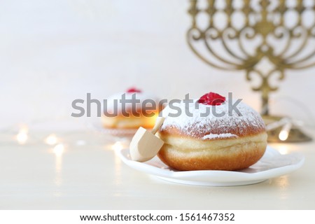 religion image of jewish holiday Hanukkah with spinning top and doughnut over white background