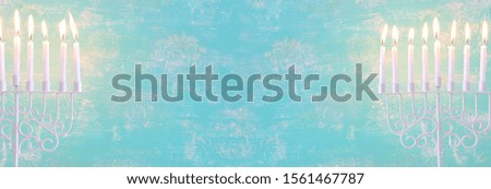 Religion image of jewish holiday Hanukkah with menorah (traditional candelabra) and candles over pastel blue background