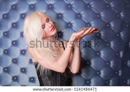 pretty blonde young woman holding tarot cards and wanna know the future on dark background