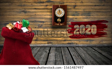 A red small bag with Christmas gift boxes in wooden room, vintage background