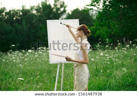 woman model on white canvas paints an easel