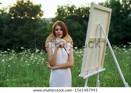 woman model on white canvas paints an easel