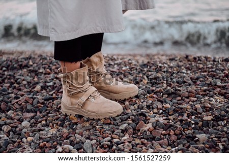 Close up photo of woman legs in boots by the sea