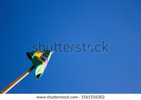 Brazilian flag stands under a blue sky