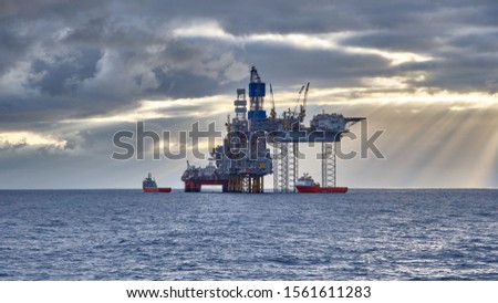 Oil and gas industry in the North Sea. View of Jack up drilling platform with supply vessels in the sea. Royalty-Free Stock Photo #1561611283