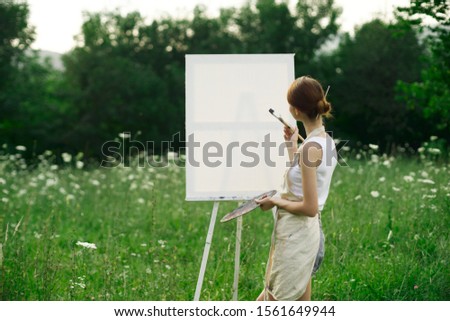 young woman on a white canvas paints a picture