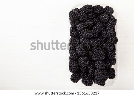 ripe blackberry in a plastic box isolated on a white background. place for text
