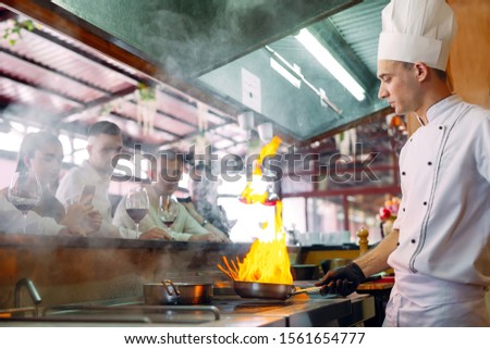 The chef prepares food in front of the visitors in the restaurant.