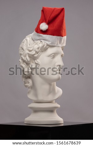 White plaster Statue of a bust of Apollo Belvedere in a red cap of Santa Claus