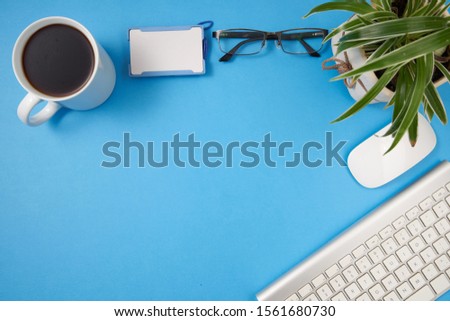 Creative flat lay photo of workspace desk. Top view office desk with keyboard and coffee cup on blue color background. 