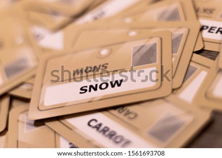 Snow word on a yellow card, shallow depth of field. Multiple cards visible out of focus. Concept of winter, ice, snowing, cold weather.