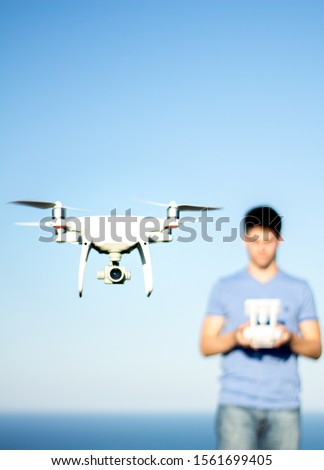 Drone flying with a blurred operator behind, maritime landscape.
