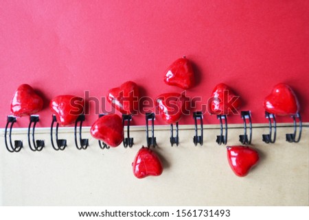 red hearts lie on the spring of the notebook. Heart scatter falling on white background. Red and crimson folded paper cut hearts. Sweet love symbols. Happy Valentine's Day, my love.